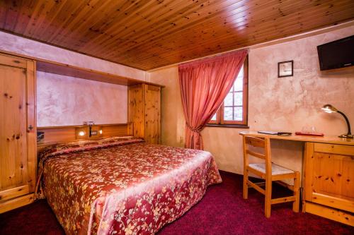 a bedroom with a bed and a desk with a computer at Hotel Des Glaciers in Courmayeur