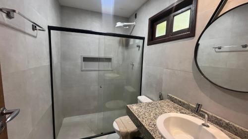 a bathroom with a shower and a sink and a mirror at Villas Pratagy Flor de Lis 901-Studio in Maceió