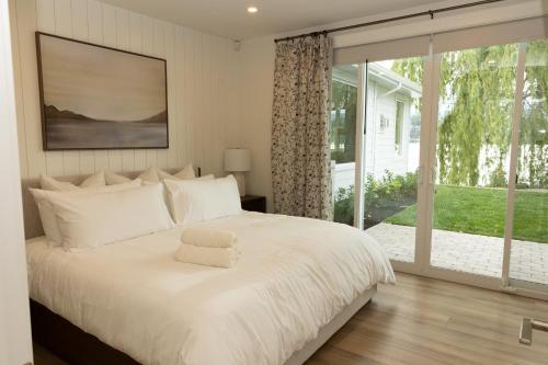 a bedroom with a white bed and a large window at The Point on Wood Lake in Lake Country