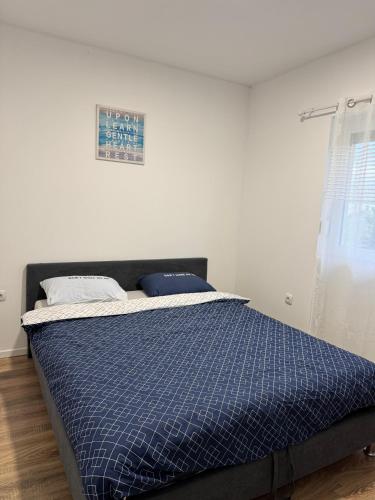 a bed with a blue comforter in a bedroom at Vikendica Fenix in Banja Luka