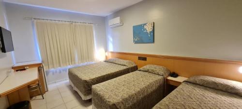 a hotel room with two beds and a window at Hotel Gumz in Balneário Camboriú