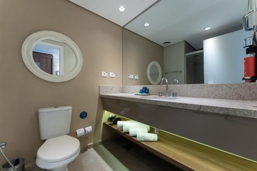 a bathroom with a toilet and a sink and a mirror at Deville Prime Campo Grande in Campo Grande