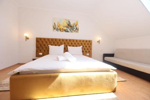 a bedroom with a large white bed and a couch at Pensiunea Cavaler in Baile Felix
