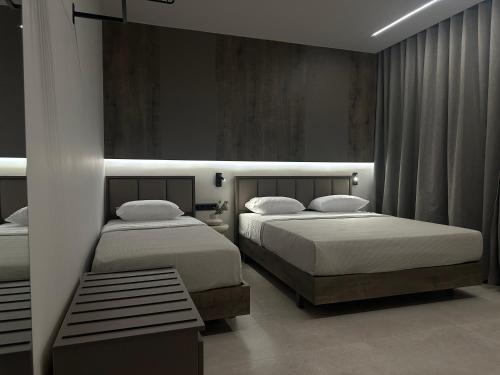 a bedroom with two beds and a bench in it at Aelith Rooms in Platamonas