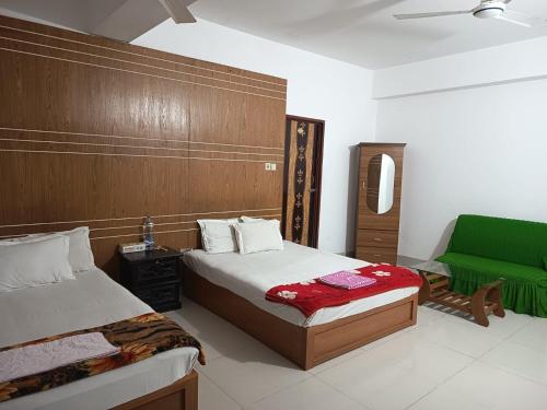 a bedroom with two beds and a green chair at HOTEL AL SAFA INTERNATIONAL, Ashkona in Dhaka