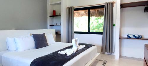 ein weißes Bett in einem Zimmer mit Fenster in der Unterkunft Valentina Holbox by Las Flores Vacation Rentals in Holbox