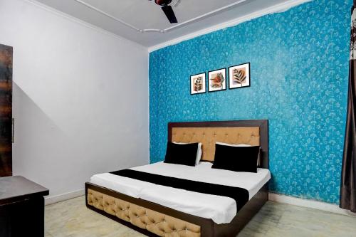 a bedroom with a bed with a blue wall at Hotel O A-1 Guest House in New Delhi