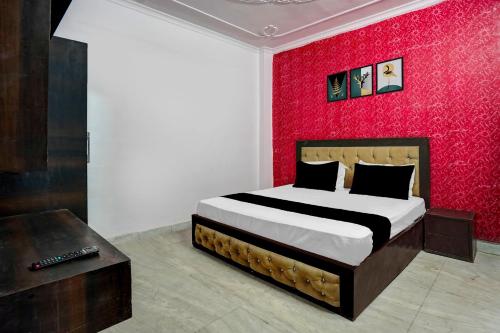 a bedroom with a bed with a red wall at Hotel O A-1 Guest House in New Delhi