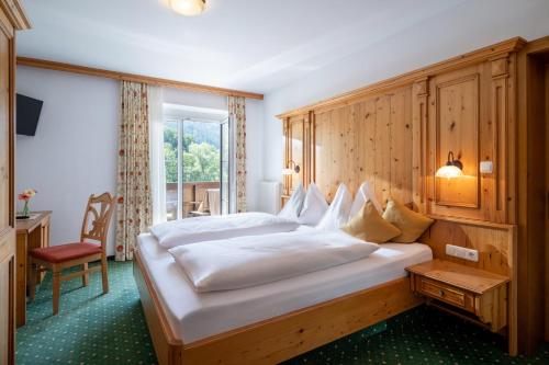 a hotel room with a large bed and a chair at Gasthof Aschenwald in Westendorf