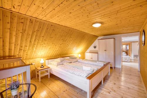 a large bed in a room with a wooden ceiling at Chata Vanilka in Bělá pod Pradědem
