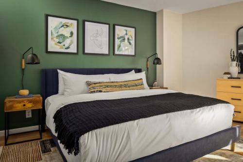 a bedroom with a large bed and a green wall at Urban Gallery Loft - King Bed - Larimer Square in Denver