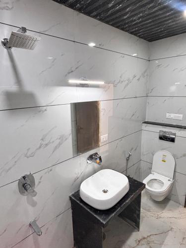 a white bathroom with a toilet and a sink at Hotel Golden Heights in Ajmer