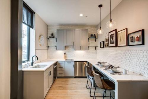 a kitchen with white cabinets and a sink and chairs at Walkable Urban Tennyson St Apt - Steps to Eats in Denver