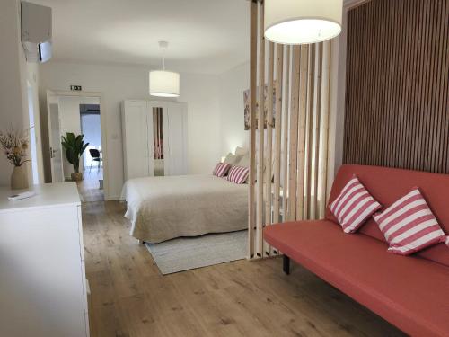 a living room with a bed and a red couch at Flor de Charme in Campo Maior