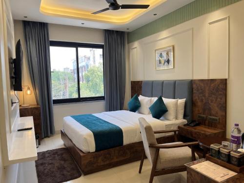 a bedroom with a bed and a chair and a window at Hotel Central Park Inn, in Dehradun