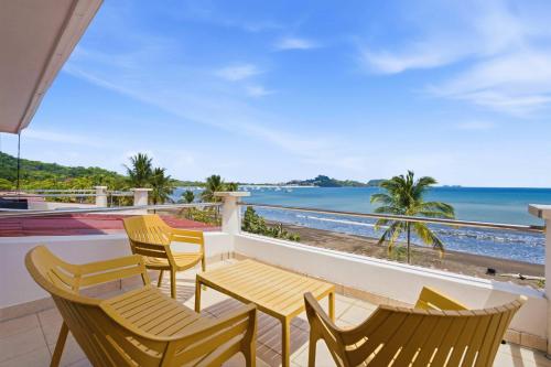 a balcony with chairs and tables and a view of the beach at Beachfront Penthouse with Panoramic Ocean Views in Playa Flamingo