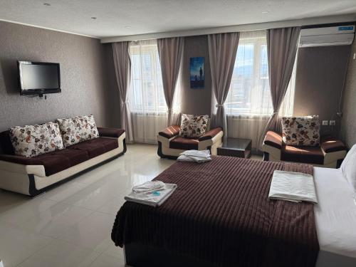 a hotel room with a bed and two couches and a tv at Lux hotel in Tbilisi City