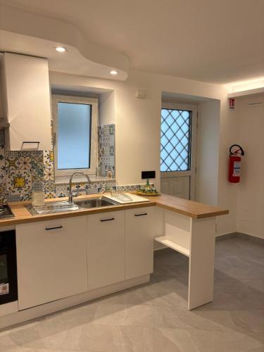 a kitchen with white cabinets and a wooden counter top at Relax nel Centro Storico in San Nicola Arcella