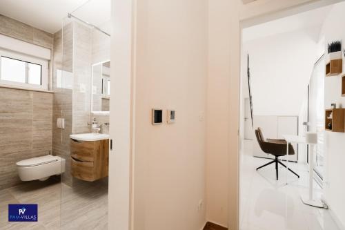 a bathroom with a toilet and a sink and a chair at Primosten Hills West - Branded Luxury Villa in Primošten