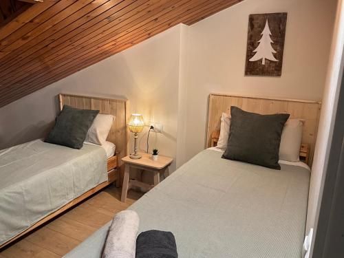 a bedroom with two beds and a table with a lamp at Escapada in Puigcerdà