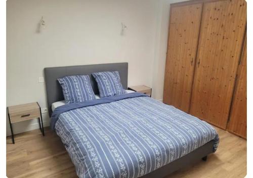 a bedroom with a bed with a blue comforter and pillows at Le Petit Logis in Beaurepaire