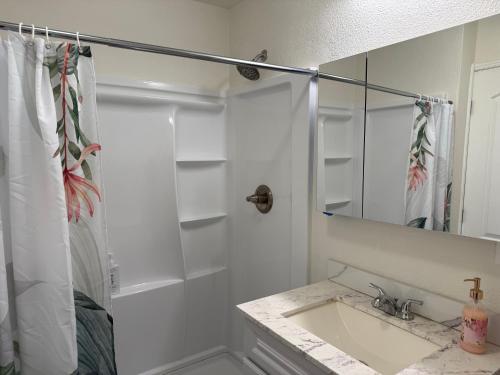 a white bathroom with a sink and a mirror at Hale Kululoa in Hilo