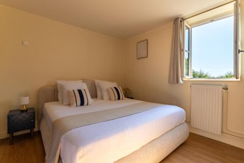 a bedroom with a large white bed with a window at Duplex de charme dans un Cloître historique Parking privé in Rouen