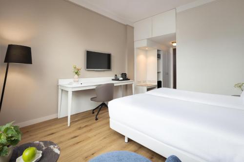 a white bedroom with a desk and a bed at NH Bussum Jan Tabak in Bussum