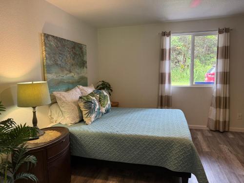 a bedroom with a bed with pillows and a window at Hale Kululoa in Hilo