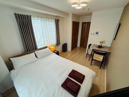 a bedroom with a large white bed and a table at NUPRIME morishita in Tokyo
