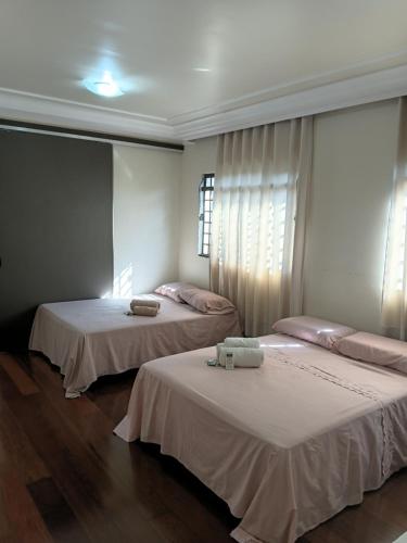 two beds in a room with white walls and wood floors at Aero Hospedagem Londrina in Londrina
