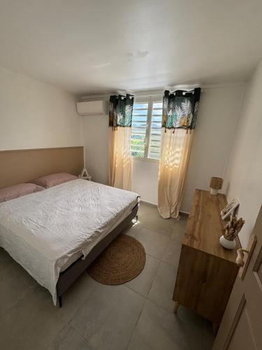 a bedroom with a bed and a window with curtains at Spacieux logement in Lamentin