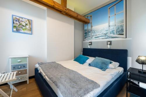 a bedroom with a blue bed and two windows at Apartamenty Centrum - Sunshine in Opole