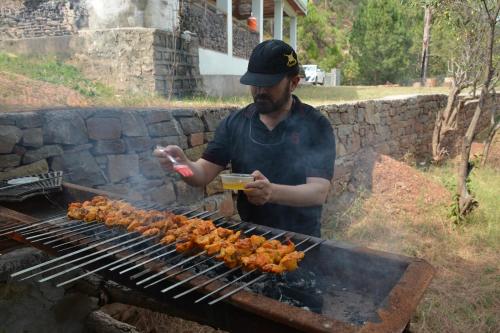 a man is cooking food on a grill at Brookside Pines in Murree
