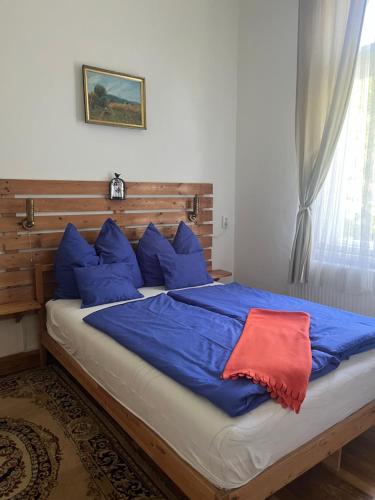 a bed with blue sheets and a red blanket at Eitner Villa Apartman in Kőszeg