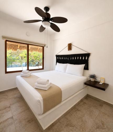 a bedroom with a large bed with a ceiling fan at Paseo Kuka by ÓOL Hotels in Holbox Island