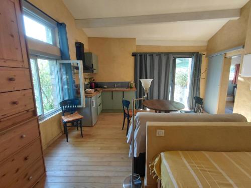 a bedroom with two beds and a table and a kitchen at La Maisonnette Veyronne - Gîte neuf in Aubres