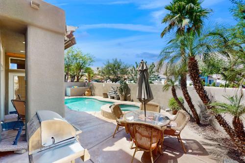 a patio with a table and chairs next to a swimming pool at Lovely La Quinta - 66318 in La Quinta