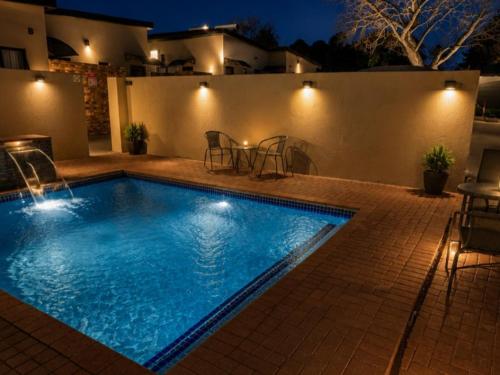 a swimming pool in a backyard at night at Grand Diamond Lodge in Roodepoort