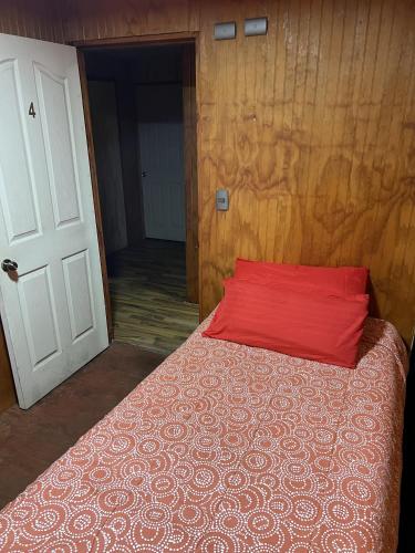 a bedroom with a bed with a red pillow on it at Hospedaje Ilabaca in Angol