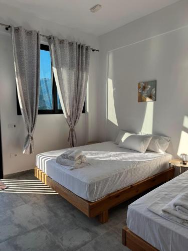 zwei Betten in einem Schlafzimmer mit zwei Fenstern in der Unterkunft Solemare in Himarë