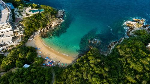 an aerial view of a beach with umbrellas and the ocean at The Sanctuary Boutique Hotel in Tangolunda