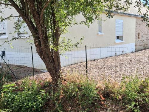 a fence with a tree in front of a building at Agréable Maison in Le Magny