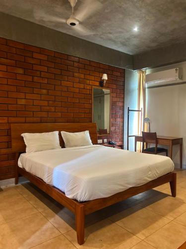 a large bed in a room with a brick wall at Savana Luxury Stay in Pondicherry