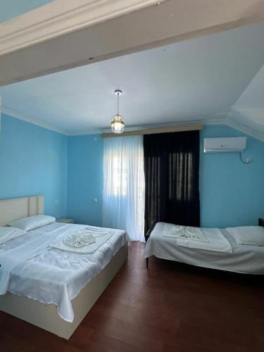 a bedroom with two beds and a blue wall at Cactus Hotel in Kobuleti
