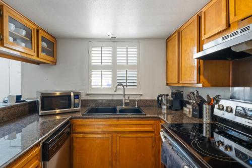 a kitchen with wooden cabinets and a sink and a microwave at Spacious Austin Loft 4BR Sleeps 12 in Austin