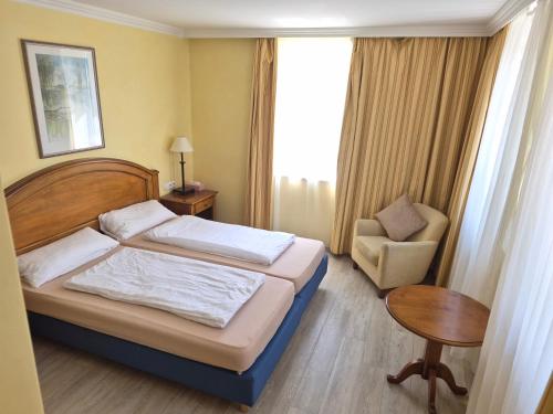 a bedroom with a bed and a chair and a table at Hotel La Strada & Sultan in Murnau am Staffelsee