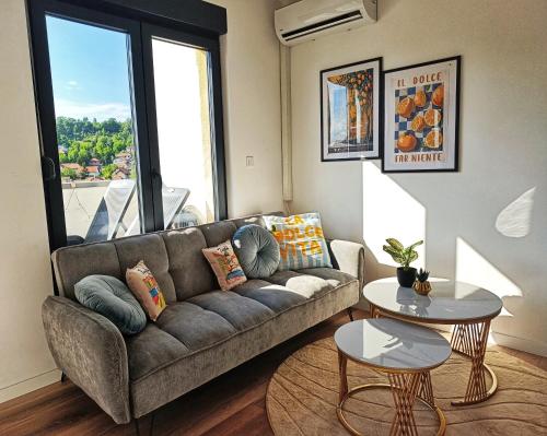 a living room with a couch and a large window at "Dolce Vita" Loft in Tuzla