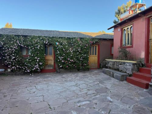 a house with a hedge with pink flowers on it at Casa de Ruben - Lac Titicaca in Llachon
