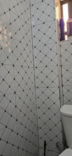 a bathroom with a white tiled wall with a toilet at Cedar Suites in Juja